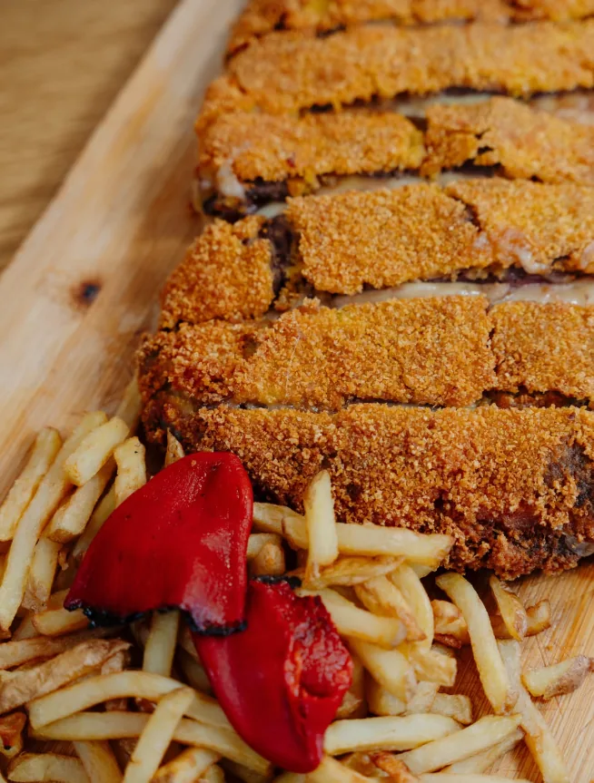 Cachopo XXL servido en tabla con papas