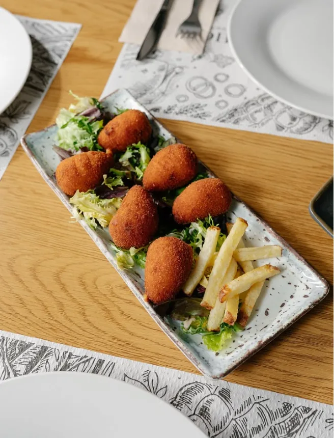 Croquetas caseras sobre cama de ensalada