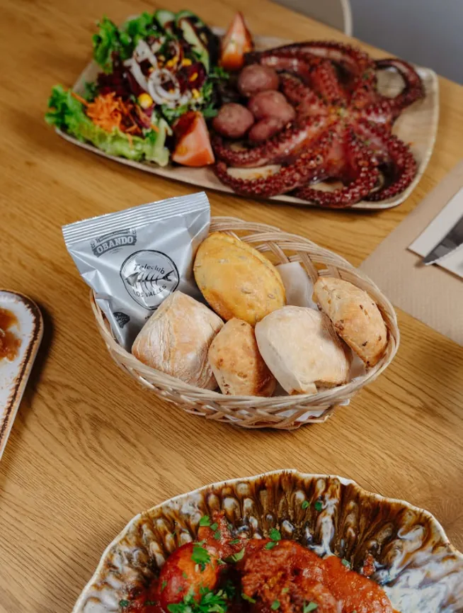 Pulpo, ensalada y cesta de pan canario en la mesa